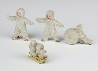 Four Victorian bisque Christmas cake decorations in the form of children - 1 pushing a giant snowball, 2 standing and 2 on a sledge (last item stuck)  
