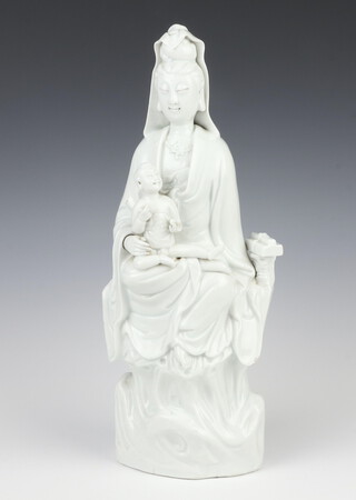 An 18th Century Chinese blanc de chine figure of Guanyin holding a child on her lap, sitting on a rustic base with bound book beside her, 39cm.   Provenance Sothebys, The Leverhulme Collection 26/27/28 June 2001 Lot 110