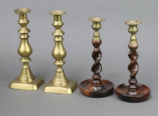 A pair of 1930's oak spiral turned candlesticks with metal sconces 26cm together with a pair of 19th Century brass candlesticks with ejectors 22cm 