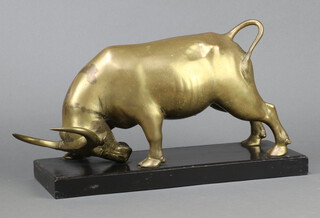 A gilt metal model of a standing bull raised on a rectangular wooden base 22cm h x 40cm w x 14cm d 