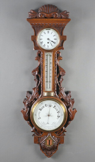 An Edwardian aneroid barometer, thermometer and timepiece with 12cm enamelled dial, Roman numerals contained in a heavily carved oak wheel case with presentation plaque "Presented to Mr W H Ffiske, on the occasion of his marriage by office staff and foreman of Boulton and Paul Ltd, Rose Lane Works, Norwich 27th June 1906"  100cm h  x 39cm 