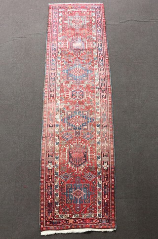 A red, white and blue ground Persian runner with 7 medallions to the centre within a multi row border 338cm x 96cm 