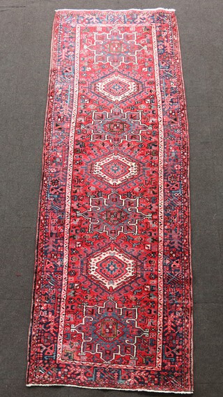 A red, white and blue Persian runner with 7 medallions to the centre, within a multi row border 303cm h x 106cm 