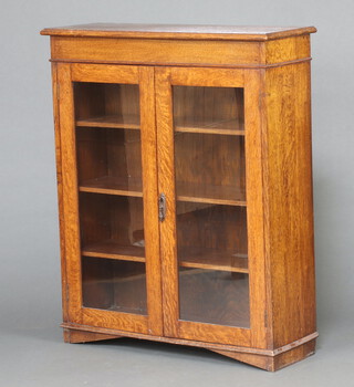 A 1920's oak bookcase/display cabinet, interior fitted adjustable shelves enclosed by pair of glazed panelled doors, raised on bracket feet 100cm h x 91cm w x 31cm d 