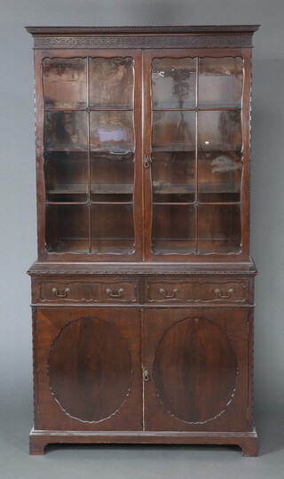 An Edwardian Chippendale style mahogany bookcase on cabinet with moulded cornice and blind fret work decoration, the shelved interior enclosed by astragal glazed doors above 2 drawers, the base enclosed by panelled doors   199cm h x 107cm w x 44cm d 
