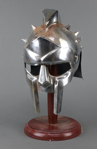 A reproduction polished steel gladiator style helmet and stand 41cm h x 20cm w x 25cm (some light rust in places)