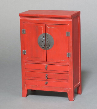 A Chinese miniature red lacquered cabinet enclosed by panelled doors above 3 drawers 36cm h x 23cm w x 12cm d 