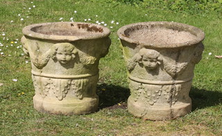 A pair of circular well weathered garden urns with swag and mask decoration 36cm h x 38cm diam. (some chips and repairs in places) 