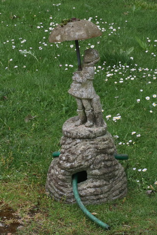 A well weathered concrete garden water feature in the form of a standing girl with umbrella 59cm h 