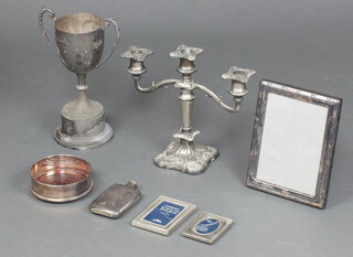 A silver plated 3 light candelabrum, a silver plated twin handled trophy cup, a bottle coaster, 3 plated frames and a hip flask