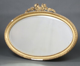 A 19th Century oval bevelled plate wall mirror contained in a decorative gilt frame surmounted by 2 quivers  75cm x 102cm (some plaster missing to frame)