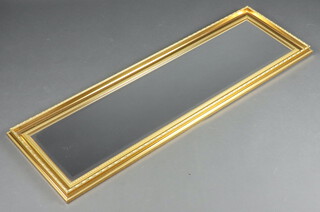 A rectangular bevelled plate mirror contained in a decorative gilt frame 133cm x 42cm 