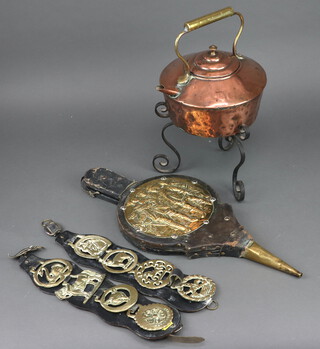 A copper kettle on a wrought iron stand, pair of bellows and horse brasses 