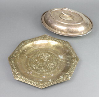 An oval silver plated entree dish and cover 29cm and an octagonal pierced and embossed brass tray decorated elephants 30cm 