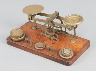 A set of brass postal scales and weights on a mahogany plinth 