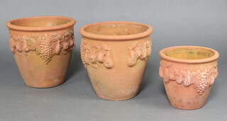 Three circular graduated terracotta plant pots with fruit decoration 