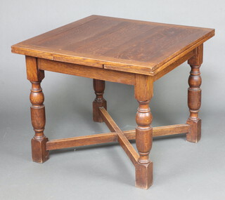 A 1930's oak drawleaf dining table raised on cup and cover supports with X framed stretcher 76cm h x 91cm w x 90cm d 