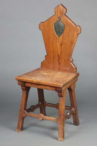 A 19th Century pitch pine hall chair, the shaped solid back with shield and monogram to the centre raised on square supports with H framed stretcher 99cm h 