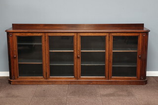 A Victorian carved rosewood bookcase with raised back fitted adjustable shelves enclosed by 4 panelled doors, 98cm h x 232cm w x 44cm d 