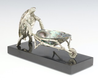 A silver plated novelty bon bon dish in the form of a standing tortoise pushing a shell wheelbarrow, on an ebonised plinth 25cm  