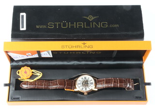 A gentleman's gilt cased Stuhrling automatic wristwatch with visible movement contained in a 43mm case on a leather strap, boxed 