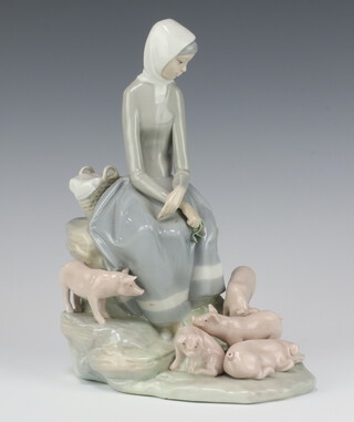 A Lladro group of a lady with piglets raised on a rocky base 24cm 