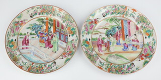 A pair of 19th Century Cantonese plates decorated with figures before pavilions, enclosed in an insect, fruit and floral border 25cm 