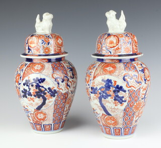 A pair of Imari oviform vases and lids decorated with panels of flowers, having shi shi finials 33cm 