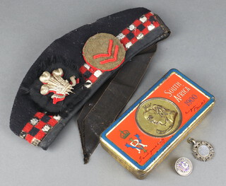 A silver watch chain medallion marked RFC Henley Golf, Won by Second Lieutenant L F Johnson 27th January 1918, a silver enamelled golfing badge marked Handicap ULG, a Boer War 1900 metal chocolate box and a Glengarry cap with Prince of Wales Feathers badge (heavily mothed)