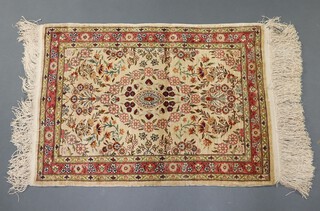 A cream and floral patterned Persian silk rug with central medallion and multi row border 67cm x 48cm 