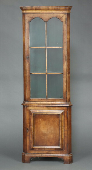 A reproduction Queen Anne style figured walnut double corner cabinet with moulded cornice, fitted shelves enclosed by glazed panelled door, the base enclosed by a panelled door, raised on bracket feet 188cm h x 86cm w x 46cm d 