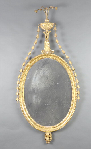 A 19th Century oval plate wall mirror contained in a decorative gilt frame surmounted by a garland and urn 110cm x 52cm 