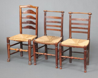 A pair of 18th Century elm ladder back dining chairs with woven rush seats, raised on turned supports 90cm h x 47cm w x 37cm d together with a similar ladder back chair 98cm h x 48cm w x 38cm d 