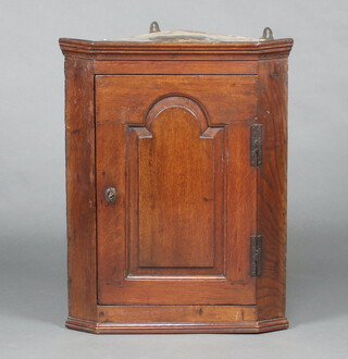 An 18th Century oak corner cabinet with moulded cornice enclosed by an arched panelled door 80cm h x 63cm w x 44cm d  