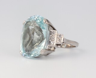 A white metal 18ct aquamarine and diamond cocktail ring, the cushion cut aquamarine 23mm h x 18mm w x 14mm d, with 10 brilliant diamonds to the shoulders approx. 0.36ct, size N, 20.7 grams 