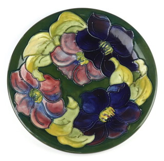 A Moorcroft plate, decorated "Clematis" on a green ground, designed by Walter Moorcroft, impressed marks and Queen Mary label 26cm  