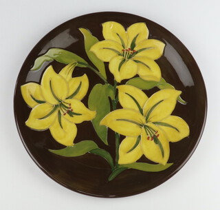 A Moorcroft plate decorated "Yellow Bermuda Lily", designed by Walter Moorcroft, impressed marks 26cm 