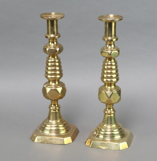 A pair of Edwardian brass candlesticks with knopped stems and ejectors, the square base marked Coronation 1902 36cm h 