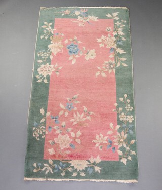 A 1930's green and pink ground floral patterned Chinese rug 179cm x 93cm 