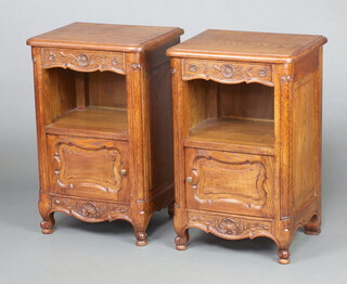 A pair of French carved oak bedside cabinets fitted a drawer above recess, cupboard enclosed by panelled door, raised on cabriole supports 70cm h x 45cm w x 36cm d 