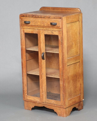 An Art Deco light oak display cabinet with raised back fitted a drawer, the shelved cupboard enclosed by glazed panelled doors 105cm h x 54cm w x 34cm d 