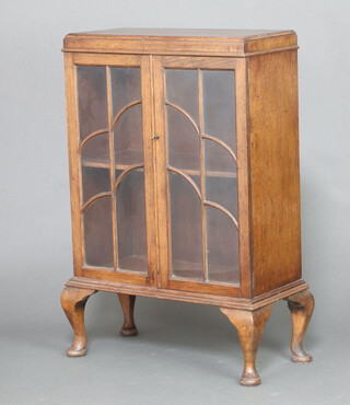 A 1920's rectangular oak display cabinet fitted a shelf enclosed by a pair of faux astragal glazed panelled doors, raised on bracket feet 91cm h x 61cm w x 27cm d 