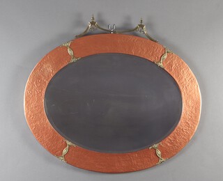 An oval bevelled plate wall mirror contained in a planished copper and brass mounted frame 60cm h x 45cm w