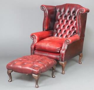 A Georgian style winged armchair upholstered in red buttoned leather, raised on cabriole supports 105cm h x 81cm w x 72cm d (seat 32cm x 34cm) together with matching footstool raised on cabriole supports 