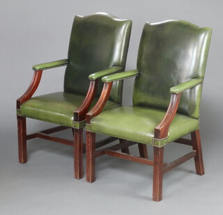 A pair of Georgian style mahogany framed open arm library chairs, the seats and backs upholstered in green leather, raised on square supports with H framed stretcher 80cm h x 59cm w x 53cm d (seats 24cm x 28cm) 