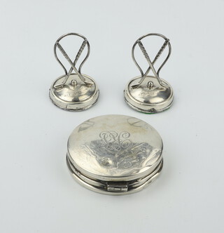 A pair of Edwardian silver novelty menu holders in the form of crossed golf clubs together with a silver compact, Birmingham 1929 