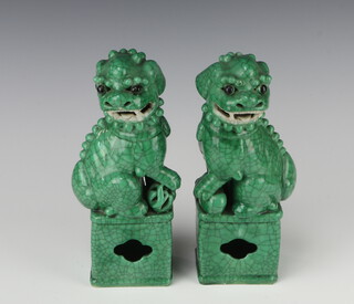 A pair of Chinese green crackle glazed figure of Shi Shi standing on rectangular bases 25cm 