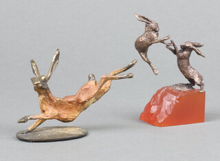 A cold painted bronze figure of a running hare 5cm together with Butler and Peach, a pair of bronze figures of boxing hares raised on an "amber" coloured base 8cm