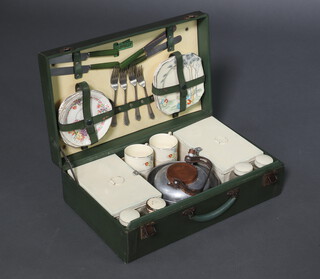 The Garrison Clovelly picnic set comprising kettle, 2 pressed metal sandwich boxes (1 with hinge a/f), 4 square glass bottles, 4 square picnic plates (2 cracked), 4 matching cups (1 chipped 1 cracked), 3 saucers (1 cracked, 1 chipped) and a near matching saucer, contained in a green fibre carrying case 14cm x 46cm x 28cm 