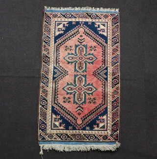 An Afghan red and blue ground rug with 2 stylised medallions to the centre 130cm x 72cm 